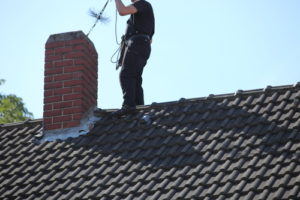 Technician chimney sweeping a home